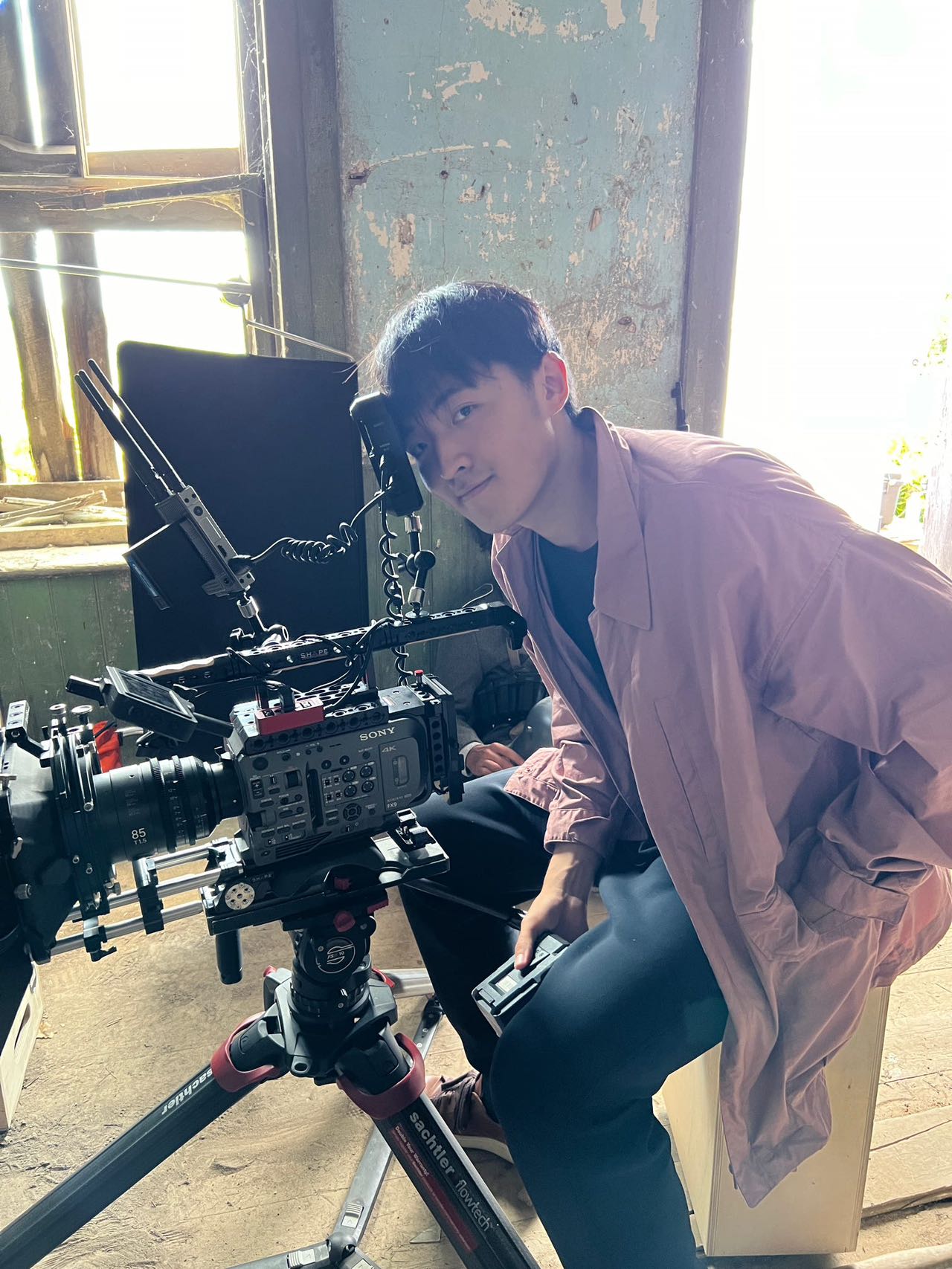 Boyi Tan beside a cinema camera and monitor on set