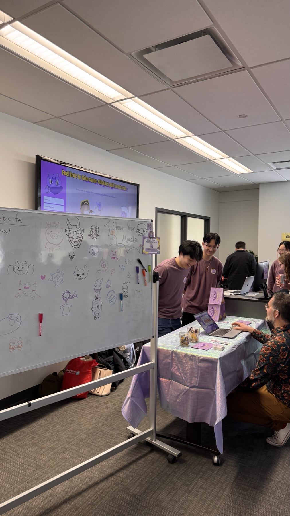 Capstone exhibition whiteboard where visitors drew their own monster ideas beside The Kindness Quest demo table